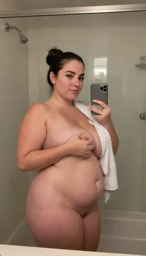 White latina milf, 45 years old, (plump:1.4), (thick:1.4), dark brown straight long hair, beautiful ass, standing in a foggy bathroom mirror after a hot shower, wearing a loosely tied towel around her body. Steam covers parts of the mirror, and her damp hair falls over her shoulders. Her skin glows softly from the warm humidity. She holds the phone with one hand, the other gently brushing her collarbone. Her eyes meet the camera with a calm, captivating expression. The photo feels intimate, like a private snapshot after a relaxing shower.