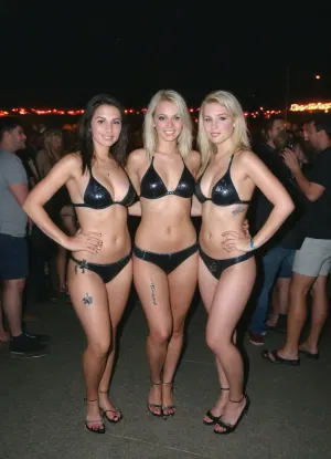 girl are 4' tall, petite, tiny, size 10 waist, slim thick, Leica M10, dslr, Wide-Angle Lens 35mm, ((extremely wide shot:1.8)), (((Wide-Angle perspective:1.8))), (((interesting angle))), (full-length image:1.9), ((rear side view:1.8)), (nighttime), (no ambient light), (single harsh flash from the camera), (overexposed flash highlights on subject), (flat lighting due to direct flash), (cool white balance:1.3), (cyan-tinted shadows from digital camera sensor), (fluorescent-like artificial lighting tint), (fluorescent lighting tint), (artificial lighting with cyan hue), (realistic dark environment with high flash contrast), (cool indoor lighting), (direct flash photography), (overexposed flash), (strong shadows), (sharp shadows), (lights off), (background remains visible due to flash, but lacks blur or depth separation), (sharp background), (background in focus), (no background blur), (clear background details), (wet surfaces reflecting small highlights), (swamp), (realistic environment), (scene "Myspace"), (2000s), (90s digital aesthetic), (Scene-Queen), (Myspace), (picture), (bad quality), (90s style), (80s), (1990s), (analogic), (analogic style), (low quality photo), (old camera), (flash photo), (old digital camera), (cellphone photography), (Polaroid flash camera), (raw), (jpeg artifacts), (film grain), (light leak), (low res), (low quality), (unfiltered), (low contrast), (low contrast:2), (noise in all darker areas), (noise in dark areas), (shiny reflections on surfaces), (gritty), (optional), polaroid, film, photography, longnightout, ((big breast)), This photograph captures three women posing together at night, likely at a party or club. The woman on the left has long, wavy blonde hair, tan skin, and wears a revealing, dark brown bikini. The woman in the center has long, straight platinum blonde hair, pale skin, and is wearing a red micro bikini. The woman on the right has long, straight black hair, light skin, and wears a black bikini adorned with silver studs and an, (((Angel tattoo on her stomach))), . They are standing close, with the background blurred, showing lights and people., <lora:Polaroidv2:1.5>, <lora:late night out_epoch_12:.8>