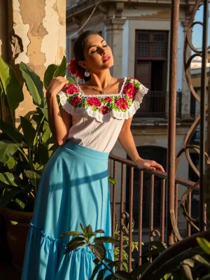 A striking image of a beautiful Cuban woman standing on a balcony in Old Havana, bathed in the warm glow of a sunset. She has her eyes closed, a serene smile on her face, savouring the golden rays of the sun on her skin. Her attire consists of a vibrant Camisa de Campesina with intricate floral patterns and a flowing sky blue Pollera skirt. The composition should include lush green foliage and old weathered walls of the colonial architecture in the background, highlighted by the rich, warm colours of the sunset. The atmosphere is joyful and tranquil. Aim for high resolution, to capture every detail vividly.