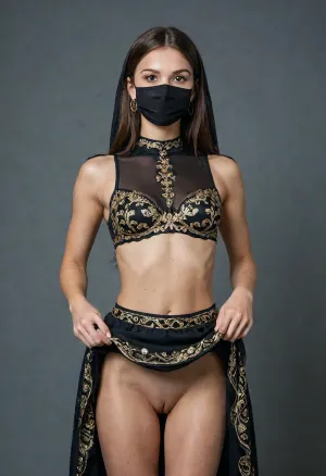 Adorned in an elaborate black and gold attire, The tall and very skinny Moroccan Amazigh woman's attire consists of a black bra, a tight black and gold skirt, a black veil on her head, and a black sheer lace mask that covers the lower half of her face, with only her eyes visible. The mask is intricately decorated with gold embroidery and chains, adding to the overall ornate appearance of the outfit. I look at you, raising my chin slightly, (girl shows her pussy by lifting up her skirt:1.3), (lifted skirt:1.2), (no panties:1.2), (pussy, smooth pussy:1.2), a slight smile playing on my lips.