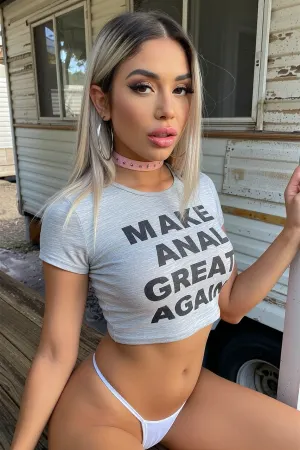 A dirty looking trailer park young slender busty Latina woman with straight hair dyed platinum blonde, tanned olive skin, expressive brown eyes, a youthful round face, ((bimbo makeup, thick full lips with bright lipstick, thick dark eyeliner, bright eyeshadow, long eyelashes with mascara)), she is posing provocatively outside her rundown old trailer home, obviously trying to make money as a sex worker. She's only wearing the tiniest white thong panties, very large silver hoop earrings, a pink choker and a tight grey shirt that has printed words on it, MAKE ANAL GREAT AGAIN