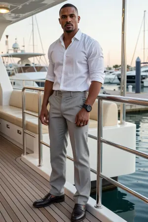 A photorealistic full body portrait of Marcus Reed, a handsome thirty-four-year-old Black former Army medic and current firefighter paramedic standing on the teak deck of a luxury yacht at an elegant marina.

Marcus is tall and powerfully built with broad shoulders, deep brown skin, close cropped black hair, dark brown eyes, and a neatly trimmed beard. A faint scar is visible near his left temple.

He wears tailored light gray trousers, a fitted white linen shirt with the sleeves rolled neatly to his forearms, and dark brown leather boat shoes. His collar is open without a tie. He wears a sturdy black watch and a plain silver wedding ring.

Marcus stands near the polished railing with his hands resting loosely in front of him. His posture is controlled and quietly protective. His expression is calm, serious, and emotionally guarded.

Behind him are chrome railings, cream colored seating, calm blue water, and an elegant marina in warm late afternoon sunlight. Cinematic psychological drama, realistic skin texture, natural proportions, subtle emotional tension, shallow depth of field, no text, no logos.