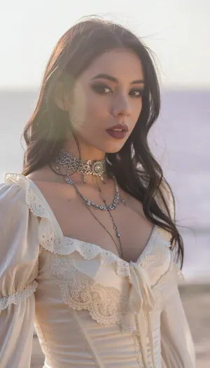 A vertical cinematic portrait with an ethereal, soft-focus aesthetic, defined by diffused light. The subject is an enigmatic young woman, framed from the chest up, with long dark hair and wispy strands that have a soft, luminous halo. She wears delicate, dramatic smoky makeup and deep matte lips. She is dressed in a soft ivory satin corset top with detailed lace ruffles and layered antique silver gothic necklaces. The scene is enveloped in a powerful but diffused golden-hour glow from the side, which creates a luminous 'light bloom' on her skin and the silk, dissolving sharp edges in an ethereal haze. The background is a very blurred, dreamlike pastoral pastel lavender-gray coastal sky, soft and bright. The overall mood is serenely melancholic and nostalgic. Shallow depth of field, subtle film grain. This is a high-key photograph.