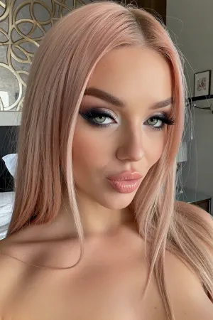 (close-up intimate candid snapshot of a slender 24yo woman with a lithe body), (soft long pink-blonde hair in a sleek stylish center-part), (mischievously coy expression in her downturned pale-green eyes framed by long thick eyelashes), (soft oval lips with pillowy creases quirked in a soft flirty smile), (she is wearing heavy dark makeup with thick kohl eye shadow and bold winged eyeliner), (luxurious modern bedroom with uncluttered tasteful decor)