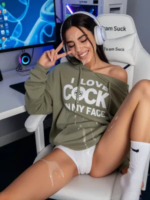 A casual "caught in the moment" photo of a 23 y.o.Moroccan amazigh tall very skinny woman with dark brown hair and brown eyes sitting on a white gaming chair at a white standing desk with a curved monitor with blue desktop wallpaper, a white gaming PC with RGB, webcam glowing in the background. Huge amounts of realistic Cum is dripping from her forehead and nose and chin and thighs, cum on her shirt, cum on her legs, the white gaming chair has a text "Team Suck" on the headrest. She is wearing an oversized olive green hoodie that hangs off one shoulder, She is wearing tight white pant shorts. She is wearing white gaming headphones with microphone. She is legs wide on the chair, wearing long white socks with Nike logo. On the hoodie there's a white big text "I LOVE COCK IN MY FACE", a logo with a penis inserted into a mouth. She is making a V sign, (peace sign), with the fingers of her right hand, eyes closed, big toothy grin showing her teeth, cute, playful expression