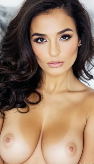 A breathtakingly beautiful Indian woman with an exceptionally stunning face, perfectly balanced and mesmerizing. Her hair is deep jet black, extremely dark and glossy, styled in long, soft, luxurious waves that frame her face elegantly. She has full, luscious, carnous lips with a natural sensual curve, slightly parted, and large almond-shaped dark eyes that radiate confidence and allure. Her skin is a warm golden-brown tone, flawless and luminous. Her expression is magnetic and sophisticated, subtly seductive yet elegant. Glamour cinematic lighting accentuates her cheekbones, jawline, and lips, soft shadows enhancing her facial beauty. High-fashion editorial style, ultra-realistic, high-definition, shallow depth of field, timeless glamour, sensual and luxurious mood.