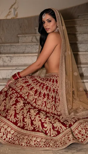 The Princess of the Palace. An adult Indian model with golden-brown skin, long black hair, and brown eyes wears a red and gold embroidered lehenga, adorned with traditional jewelry and a sheer veil. Posing sideways on a marble staircase—with the fabric fanned out around her legs and her face turned toward the camera—she embodies a blend of majesty and sensuality.