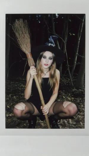 petite young witch holding broomstick, cute 18 year old, wearing witches hat, torn stockings, scary make-up, halloween, night time, forest, high cheekbones, fully lips, candid photo, amature picture, polaroiid, 80's