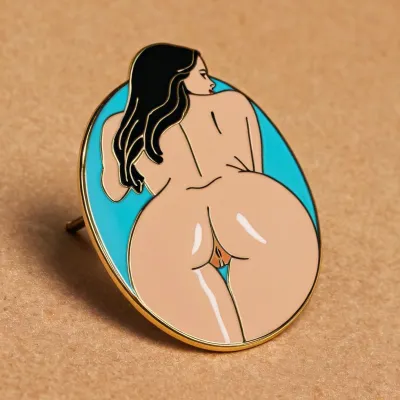 an enamel pin of a woman's ass, other enamel pins of naked women fill the board around it, flat color pin