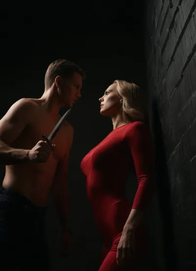 (Dutch angle:1.4), (view from below:1.4), The image is a 3D rendering depicting a dramatic scene., (two persons depicted – one woman and one man:1.6), A slender, fair-skinned woman with long blonde hair is bound to a metallic wall. Her wrists are secured, and her pose suggests forced restraint. She's wearing a red, form-fitting bodysuit that resembles a lingerie-style leotard. Her expression is one of apprehension or fear. She's wearing high-heeled red shoes. A man partially obscured by shadow stands to the left, (holding a knife:1.4), . He's wearing a white T-shirt jeans and a hockey mask that covers most of his face. His stance and the knife suggest a threatening or dangerous presence. The backdrop is a metallic wall with a diamond-plate pattern, giving a feeling of cold, industrial confinement. The lighting is dramatic, highlighting the woman and the man's knife, while casting the background in partial darkness. The image conveys a sense of tension, suspense, and potential violence. The contrast between the woman's vulnerability and the man's menacing posture creates a powerful and unsettling effect. The overall tone is dark and suggestive of a dangerous encounter, 8K ultra HD, DRSL photo