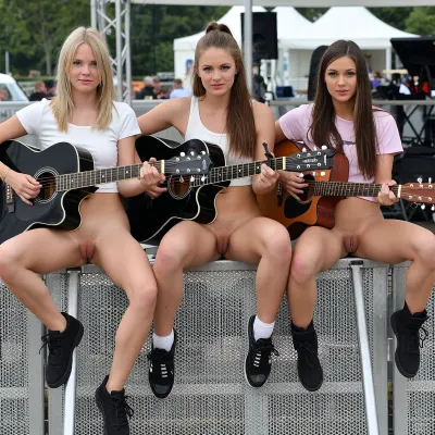 Three female musicans eith guitars sitting side by side in a row at the edge of a festival area. Spread legs, proudly presenting their pussies, voyeur photo, focus on vaginas