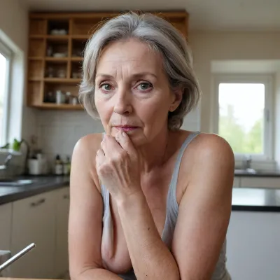 In einer Küche, Eine ältere, dicke, üppig gebaute, 65jährige Frau mit Kürbisgroßen 42FF Brüsten und grauen Haaren, sitzt breitbeinig auf der Küchenzeile und steckt ihren Mittelfinger in ihren Anus