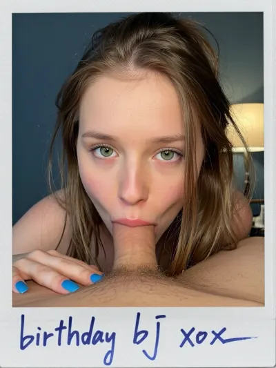 Mans POV. A close-up, intimate portrait of a young woman with fair skin and green eyes, her face positioned on a man's torso, her mouth just above his penis. She has long messy Beliage hair that frame her face. Her expression is direct and engaging, with wide eyes and slightly parted lips. She wears bright blue nail polish. The composition is tight, focusing on her face and upper torso as she leans forward, cum shooting into her mouth. The lighting is soft and warm, likely from a nearby lamp visible in the background, casting a gentle glow on the scene. The background is a simple, dark blue wall, keeping the focus on the subjects. The overall style is realistic and intimate, with a shallow depth of field that blurs the background slightly., ((Polaroid Photo handwritten signed with sharpie "birthday bj xox"))