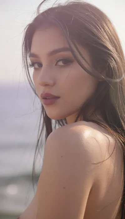 A vertical cinematic portrait of an enigmatic young Latina woman as she glances back over her shoulder, with an ethereal, soft-focus aesthetic, defined by diffused light. Her long dark hair is suffused in a soft luminous halo as it falls loosely across her face and obscuring her elegant facial features. She wears dark smoky makeup and long feathery eyelashes that highlight her oversized sensual eyes, while her soft full lips are a deep matte berry. She has high sharp cheekbones and a small mouth and chin.

The scene is enveloped in a powerful but diffused golden-hour glow from the side, which creates a luminous light bloom on her skin, dissolving sharp edges in an ethereal haze. The background is a very blurred, dreamlike pastoral pastel lavender-gray coastal sky, soft and bright. The overall mood is serene contentment. Shallow depth of field, subtle film grain, light leaks, vintage analog lens. This is a high-key photograph.