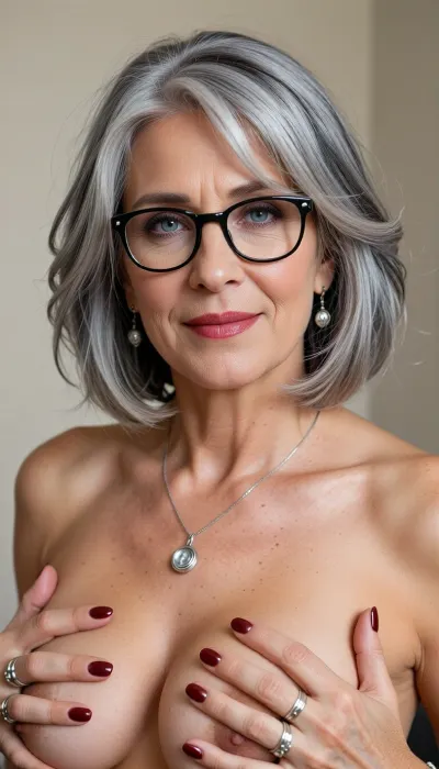 (Photorealistic portrait:65), 65 year old woman, beautiful 65-year-old woman. Paying particular attention to her hair.
Color, Silvery-white with subtle natural light-grey undertones, soft dimensional shading—brightest silver at the crown and face-framing strands, gently darker ash-grey at the roots and underlayers for depth.
Cut & Shape, Short, textured, layered bob—approximate length, jaw-length to just above shoulders. Fullness and volume concentrated at the crown and top, layers are soft and feathered, not blunt.
Front & Bangs, Soft, wispy, curtain-style bangs that blend seamlessly into side layers—parted slightly off-center, sweeping gently toward the temples, never heavy or straight-cut.
Texture & Flow, Wavy, tousled, naturally soft movement—strands appear light and airy, with individual fine-to-medium thickness visible. Sides frame the face, tapering softly near the ears, back has gentle fullness without bulk.
Styling Finish, Polished yet relaxed—no harsh shine, soft natural volume, strands fall loosely to frame forehead and cheekbones, some fine face-framing pieces lift lightly for a lived-in, elegant softness. She wears black round glasses with silver accents, soft grey eyeshadow, red lipstick. Silver drop earrings, silver pendant necklace, multiple silver rings. Named Joanna, she has bright, clear grey-blue eyes that stand out vividly, accentuated with dark eyeliner, large pupils, (natural beauty:1.2), english roots, perfect slutty smokey makeup, manicure, glossy dark red fingernails, She has expression lines and fine wrinkles under her eyes. Her body is gently wrinkled, with a generous, sagging bust with prominent nipples and soft buttocks. Warm friendly smile, soft indoor lighting, plain light wall background, natural lifelike details.