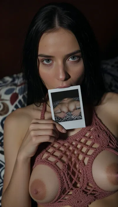 (Full view breasts:2), A close-up, high-quality of a young woman with straight long black hair, looking directly into the camera with an intense and slightly melancholic expression. Her light-colored eyes are fixed on the viewer. She is holding a small, square nude autoportrait instant polaroid photograph, (shows her lying on a patterned bedspread, hands positioned on her pubic area), between her lips. The lighting is moody and dramatic, with a focus on her face, creating a soft glow around her features while the background fades into deep shadow. She wears a burnt rose crocheted halter mesh top, (mesh top:1.9), (top grid:1.9), (transparent top:3), (Areola exposed:2), (open-knit texture:1.9), (((crocheted see through top:1.9))), (Her breasts in a top:1.5), (woman wears inesh top:2), (her the tits is covered by a wear:2), (breasts half covered:1.9), (tits covered:2), The style is reminiscent of stylized digital character art, capturing a cinematic and intimate moment with realistic textures on skin and hair, amateur aesthetic, high detail, sharp focus, atmospheric lighting.