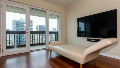 The scene is a high-rise apartment, skyscraper, large floor to ceiling windows, aged mahogany floors, a cream colored leather chaise lounge, a large Golden pathos, 75 inch TV on the wall, a balcony.