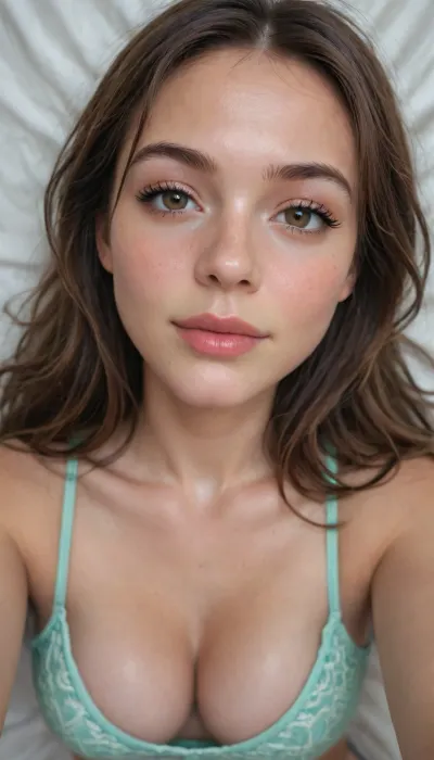 photorealistic young woman, extreme close-up high angle view from above, long brown hair with soft waves and bangs, fair skin, brown eyes looking up at camera, long lashes, glittery eyeshadow, pink blush, glossy lips slightly open in a smile, face and chest covered in white creamy fluid, large breasts, deep cleavage, light mint green ruffled crop top, lying on bed, top-down selfie angle, patterned bed sheets, soft indoor lighting, sharp focus, detailed skin texture, masterpiece, best quality, ultra detailed, photorealistic
