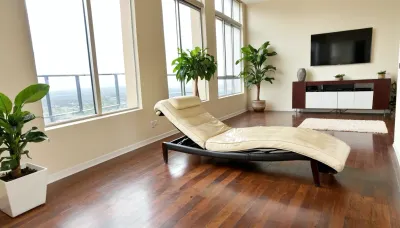 The scene is a high-rise apartment, skyscraper, large floor to ceiling windows, aged mahogany floors, a cream colored leather chaise lounge, a large Epipremnum aureum, money plant, a 75 inch TV is on the wall, a balcony.
