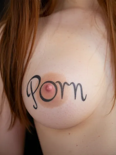 this is an amateur photo taken from smartphone, bad quality photo. The lighting is soft overhead diffused.

Long redhead hair, an extreme close-up of a perfect perky breast.

the breast is in fair skin and has a tattoo. the tattoo says 'Porn'. the 'o' from 'Porn' is actually de nipple, so the 'P' is on left side of the nipple and the 'rn' is on right side, the nipple has a black outline.