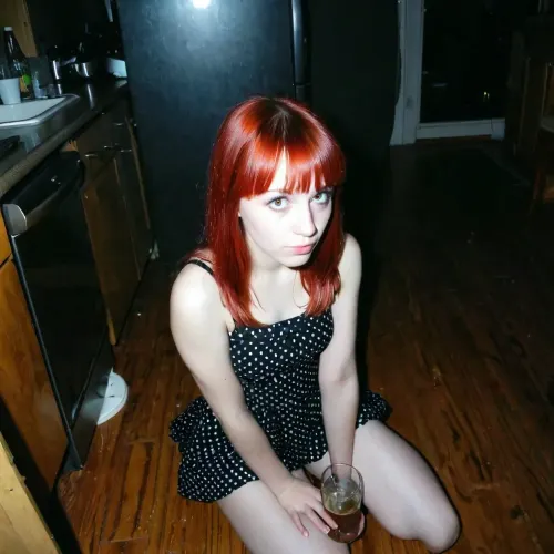 La introvertida chica grunge pelirroja con flequillo, capturada en un rincón oscuro en una fiesta en 1997, siempre estaba buscando algo más que encajar y conformarse con las normas sociales. Su cámara era su compañera mientras capturaba