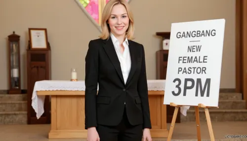 A petite woman is wearing a black pantsuit with white blouse, she has shoulder-length blonde hair, in a modern church. Next to her stands a poster stand. On the poster in the stand is text printed in large letters "GANGBANG NEW FEMALE PASTOR 3PM".