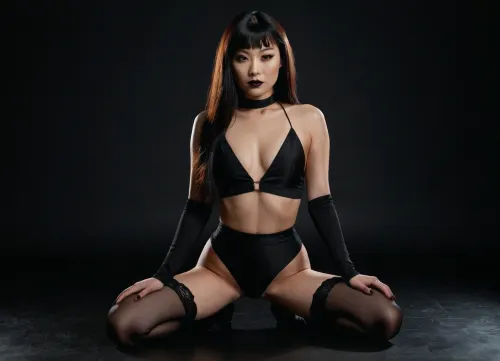 Actress Hana Mae Lee sensual figure, smooth glowing skin, brown eyes, blank semi-long hair, kneeling on a soft surface. Her back is slightly arched, hands resting on her thighs, a tattoo small at her left leg, a goth style makeup, black lipstick, black painted eyes, head tilted gently to the side with an alluring expression. Shot in a minimalist studio with dramatic lighting that creates subtle shadows across her body, ultra-detailed photorealism, perfect anatomy, lifelike detail, cinematic photography, 8K HDR..