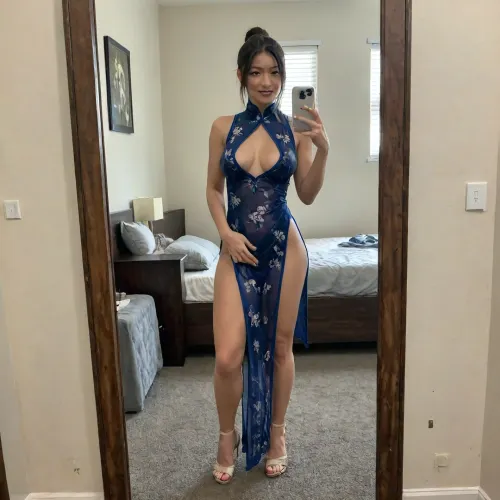 A middle-aged, voluptuous married Japanese woman takes a selfie in a mirror, wearing a qipao, reveals her breasts, shapely long legs, and sexy see-through underwear. She holds a mobile phone in her hands