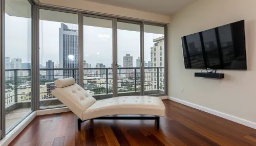 The scene is a high-rise apartment, skyscraper, large floor to ceiling windows, aged mahogany floors, a cream colored leather chaise lounge, a large Golden pathos, 75 inch TV on the wall, a balcony.