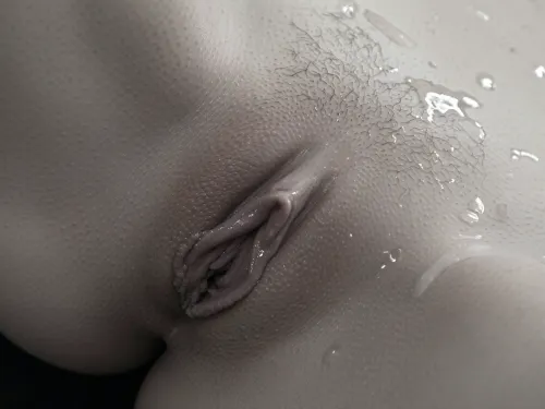 Extreme close-up of a realistic female vulva, highly detailed monochrome black and white photography, soft diffused lighting from the upper left creating subtle highlights and deep shadows that emphasize every pore, fine skin texture, tiny raised bumps, and natural wrinkles. Outer labia majora with slightly rough, pebbled surface texture, inner labia minora slightly protruding and folded with soft, fleshy, organic contours and delicate creases. Visible fine pubic hair follicles and sparse short hairs near the top, natural skin imperfections. Glossy wet sheen of moisture covering the labia and folds, small glistening droplets and thin shiny film of natural lubrication catching the light, wet reflective surfaces in the creases. Hyper-realistic skin detail, dermatological accuracy, shallow depth of field, sharp focus on the central labia, soft fall-off toward the edges. Artistic nude photography style, high contrast grayscale, 8k resolution, photorealistic, no color, no makeup, natural anatomy.