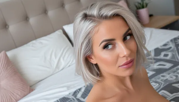 intimate portrait of a sultry woman posing sensually in her cozy bedroom with minimalist feminine decor, huge expressive eyes looking away in a coyly suggestive side-eye glance, her voluminous silvery-blonde hair in a cut in a short bob with one side swept back in a tousled finger combed look, her soft glossy lips are quirked in a smug smirk, delicate triangular face with high chiselled cheekbones, high-angle shot as she sits on her bed, the subject is anchored to the side image with her bed featured prominently in the background using a rule-of-thirds composition