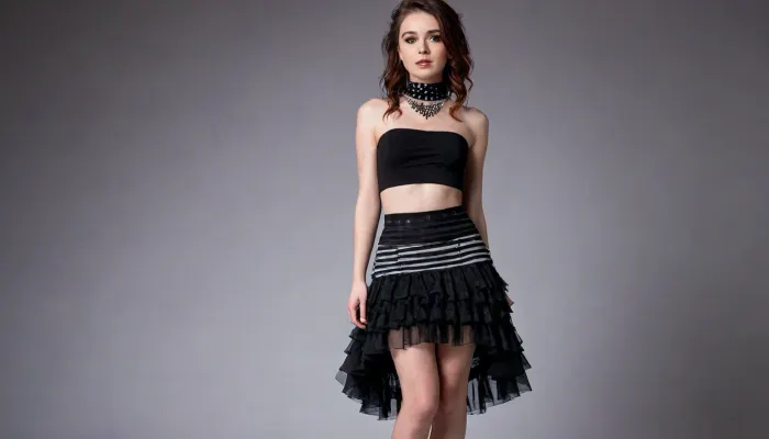 full body view, wide angle, NSFW, The skirt is a layered design with black and white striped fabric and black tulle overlays, featuring intricate polka-dot patterns and ruffled accents that add volume and movement. The combination of textures creates a rich, visually dynamic ensemble. A black choker with a small pendant adorns her neck, perfectly complementing the gothic aesthetic of the outfit., <lora:flat_chested_v3.5:.5>, <lora:nudity_v02_i1300:.5>