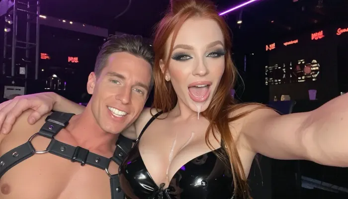 8k uhd, dslr, highest quality, full body view, man and woman, selfie after sex in a swinger Club, man has brown hair and is wearing a harness, man lays his arm around woman, both are smiling into camera, The woman has long red hair as a messy updo, she is wearing a shiny black latex bra, Woman has elegant makeup with glossy lips and dark metallic mascara eye makeup with fake lashes, excessive ultra-realistic cum on her cleavage and cum on her face